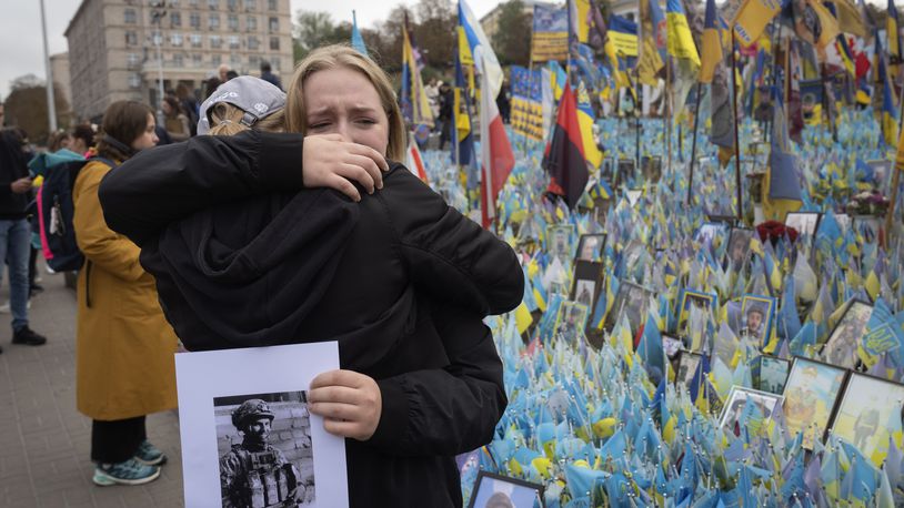 People react during a nationwide minute of silence in memory of fallen soldiers, who defended their homeland in war with Russia, on Defenders Day at the improvised war memorial in Independence square in Kyiv, Ukraine, Tuesday, Oct. 1, 2024. (AP Photo/Efrem Lukatsky)