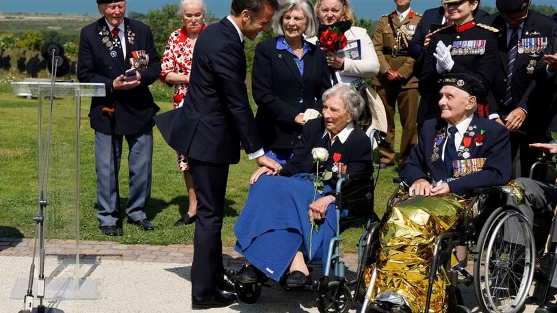France's President Emmanuel Macron reacts after awarding 104-years-old British World War II veteran Christian Lamb, center, who helped to plan the D-Day landings in Normandy, with the insignia of Knight in the Legion of Honor order, during a commemorative ceremony marking the 80th anniversary of the World War II D-Day Allied landings in Normandy, at the World War II British Normandy Memorial of Ver-sur-Mer, Thursday, June 6, 2024. Normandy is hosting various events to officially commemorate the 80th anniversary of the D-Day landings that took place on June 6, 1944. (Ludovic Marin/Pool via AP)