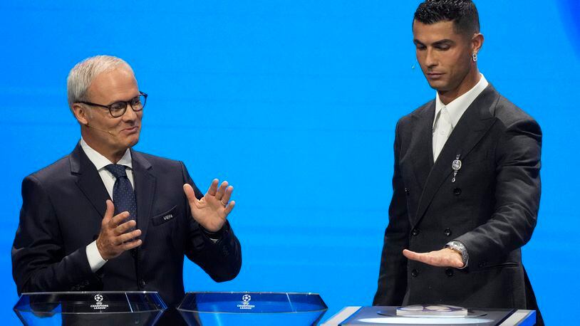 UEFA's Giorgio Marchetti watches player Cristiano Ronaldo press a button to proceed with the Champions League, league phase, draw, in Monaco, Thursday, Aug. 29, 2024. (AP Photo/Gregorio Borgia)