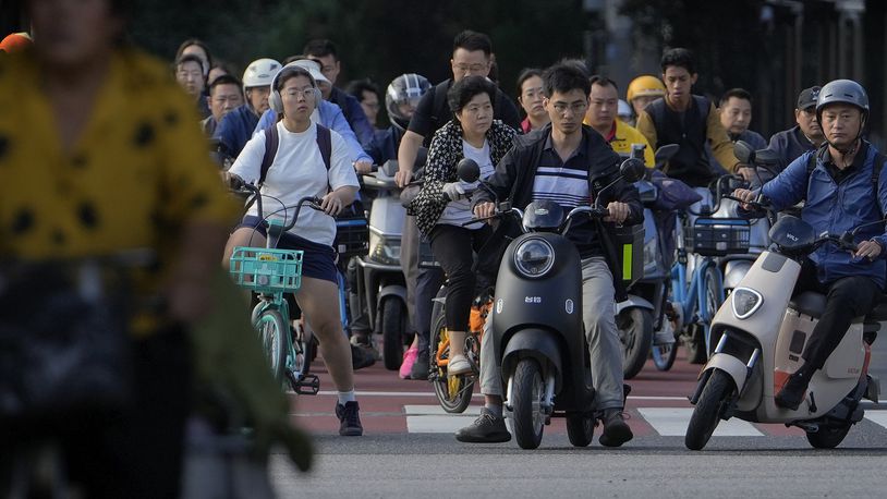 People on their bicycles and electric bikes wait at a traffic lights junction during the morning rush hour in Beijing, Friday, Sept. 13, 2024. (AP Photo/Andy Wong)