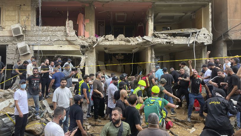 People gather near a damaged building at the scene of an Israeli missile strike in the southern suburbs of Beirut, Friday, Sept. 20, 2024. (AP Photo/Bilal Hussein)