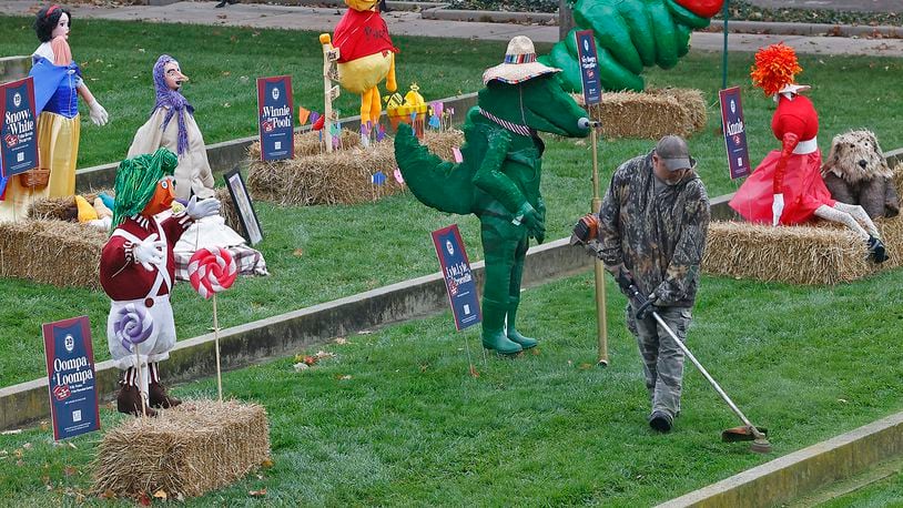 A worker from the National Trail Parks and Recreation District trims the grass around the Project Scare-A-Crow display at National Road Commons Park Monday, Oct. 16, 2023. BILL LACKEY/STAFF