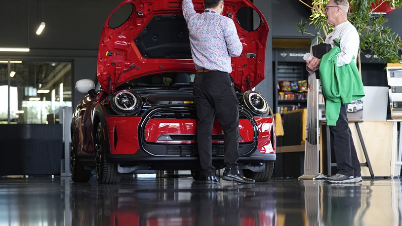 FILE - A salesperson shows an unsold 2024 Cooper SE electric hardtop to a prospective buyer in the showroom of a Mini dealership Wednesday, May 1, 2024, in Highlands Ranch, Colo. (AP Photo/David Zalubowski, File)