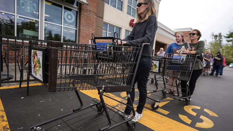 People wait to buy groceries as they stand in line outside an Ingles grocery store in the aftermath of Hurricane Helene, Monday, Sept. 30, 2024, in Asheville, N.C. (AP Photo/Mike Stewart)