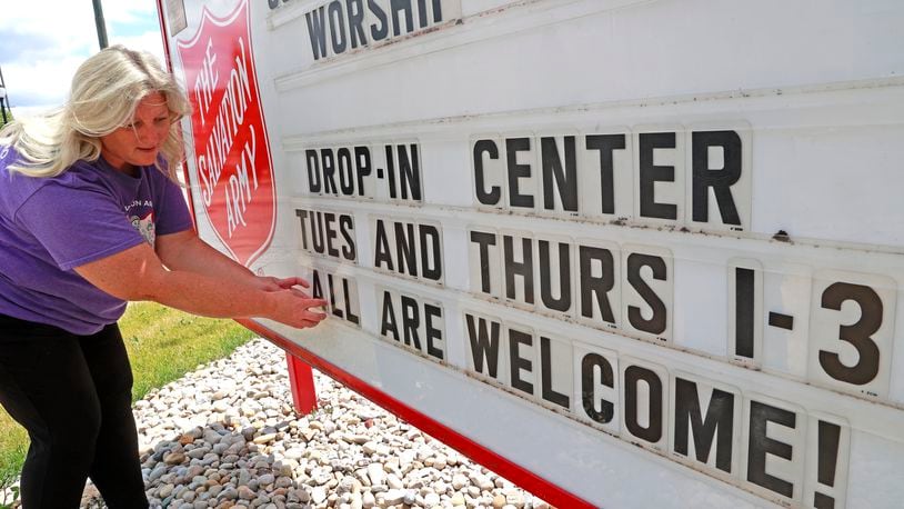 Jamie Scanlon, social ministries director at the Springfied Salvation Army, works on the sign in front of the Salvation Army advertising the Drop-In Center Wednesday, June 14, 2023. BILL LACKEY/STAFF