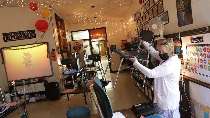 Clark and Champaign county school district coronavirus cases have dropped by over 50. Here, Sarah Covac takes the chairs off the desks in her 5th grade classroom at South Vienna Middle School. BILL LACKEY/STAFF