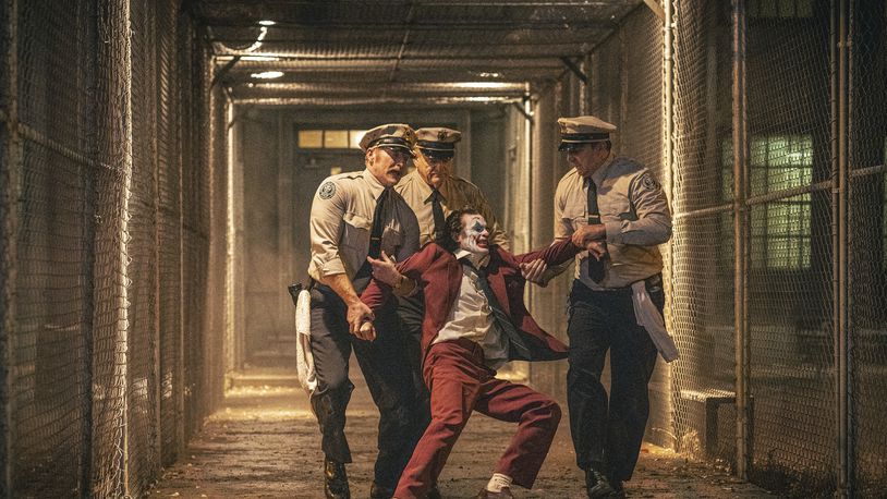 This image released by Warner Bros. Pictures shows Joaquin Phoenix, foreground center, and Brendan Gleeson, background center, in a scene from "Joker: Folie à Deux." (Niko Tavernise/Warner Bros. Pictures via AP)