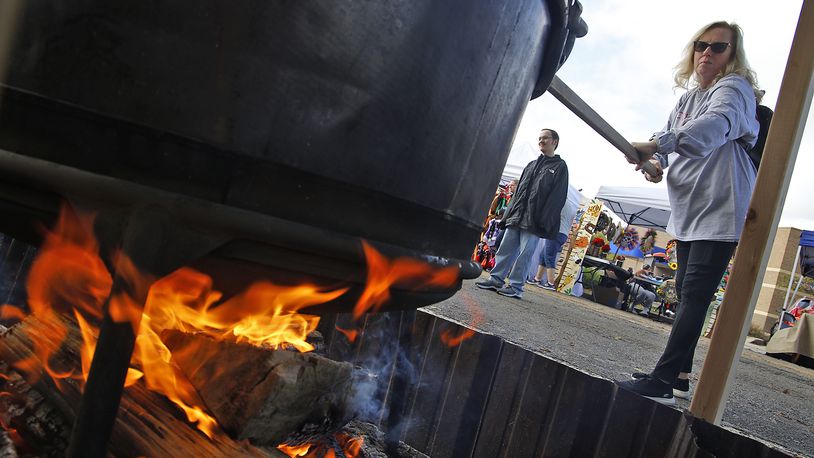 Cindy Leist takes a turn stirring one of the cauldrons of apple butter cooking over an open fire at the Enon Apple Butter Festival Saturday, Oct. 14, 2023. BILL LACKEY/STAFF