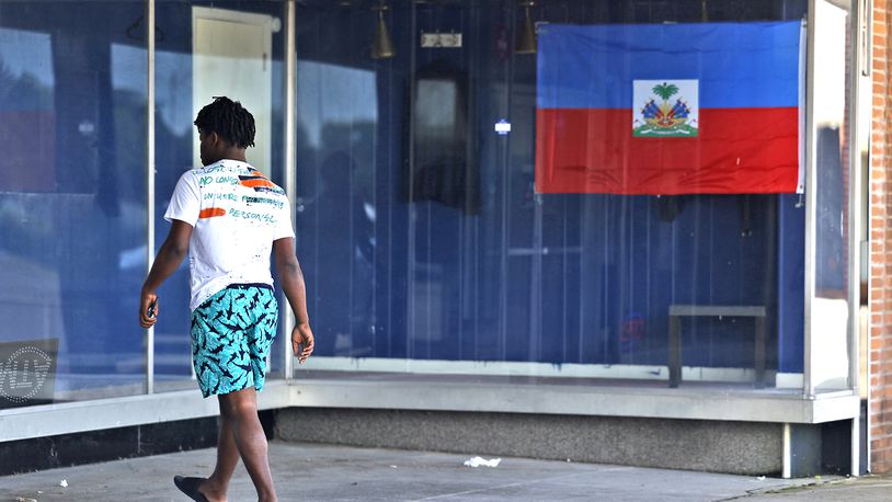 A man walks past a Haitian flag as he enters a Haitian-owned business in the Southern Village Shopping Center Monday, July 15, 2024. BILL LACKEY/STAFF