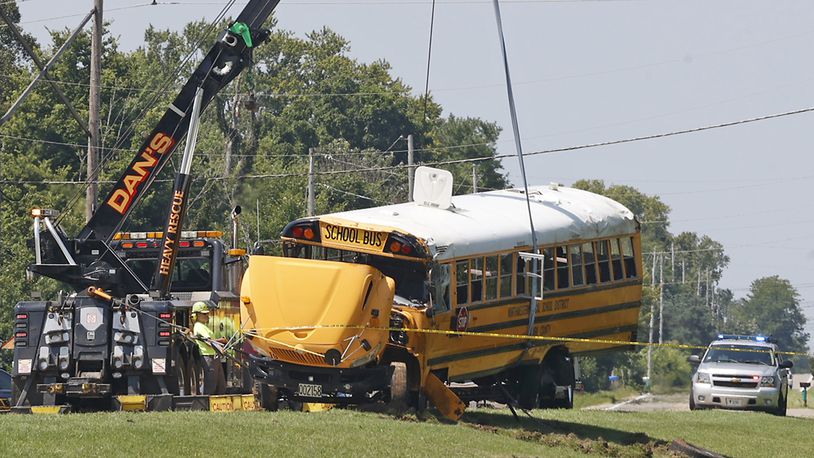 A Northwestern School District bus is uprighted by a crane after it was involved in a crash with another vehicle and rolled over in Lawrenceville, Ohio, Tuesday, Aug. 22, 2023. (Bill Lackey/The Springfield News-Sun via AP)