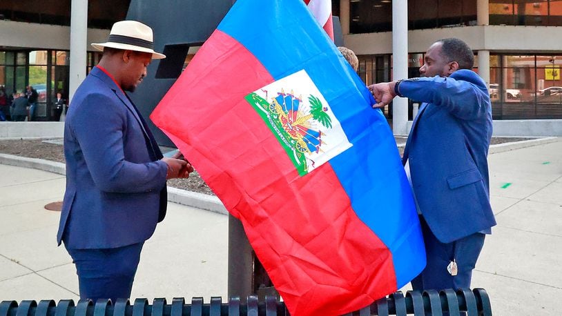 Miguelito Jerome, left, and Luckens Merzius raise the Haitian flag Thursday, May 18, 2023 in front of the Springfield City Hall. The flag raising ceremony was to mark the beginning of Flag Day in Haiti and to recognize the growing number of Haitians in the city. BILL LACKEY/STAFF