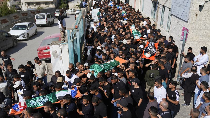 Mourners carry the bodies of 18 Palestinians who were killed in an Israeli airstrike during their funeral in Tulkarem, Friday, Oct. 4, 2024. (AP Photo/Nasser Nasser)