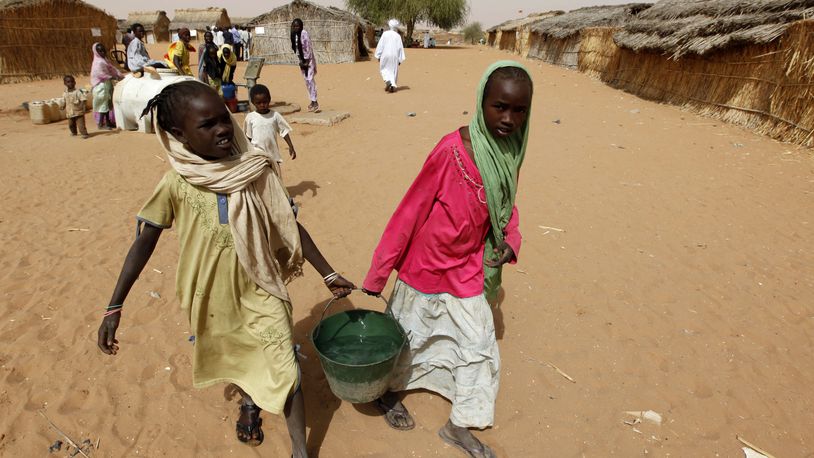 FILE - Sudanese refugee girls carry water supplies near a polling station in the refugee camp of Zamzam, on the outskirts of El Fasher, Darfur, Sudan, on April 13, 2010. (AP Photo/Nasser Nasser, File)