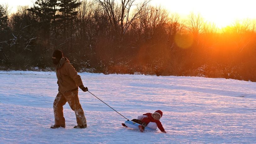 A man pulls his young daughter up the snow covered hill at Reid Park after sledding down at sunset. BILL LACKEY/STAFF