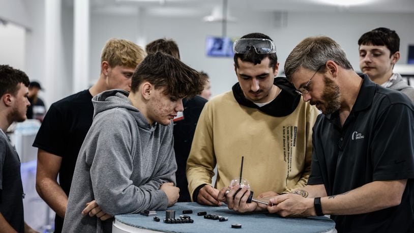 T.J. Vieira, right, a software technician for United Grinding in Miamisburg demonstrates how to measure the size of a bore. United Grinding held a manufacturing day in 2022 at the plant hosting seven school and over 200 high school students to learn about career paths in manufacturing. JIM NOELKER/STAFF