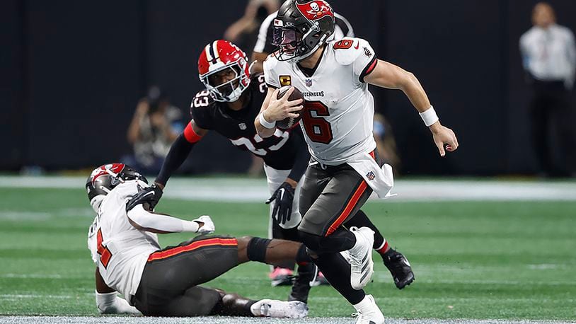 Tampa Bay Buccaneers quarterback Baker Mayfield (6) runs way from Atlanta Falcons cornerback Antonio Hamilton Sr. (33) during the second half of an NFL football game Thursday, Oct. 3, 2024, in Atlanta. (AP Photo/Butch Dill)