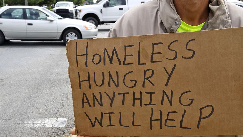 A homeless man holds a sign asking for help at the intersection of West North Street and North Bechtle Avenue Thursday, May 30, 2024. BILL LACKEY/STAFF