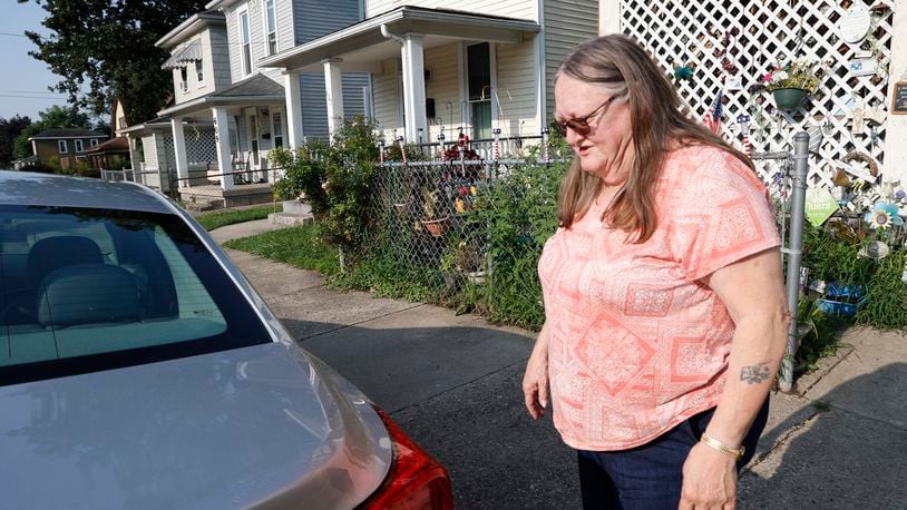 Dee Flack looks over her car as she cleans up after her neighbor, who lived in the house beside hers, was shot Tuesday night in front of her duplex in the 600 block of York Street in Springfield. Flack said she had just went to bed when she heard the shots outside. BILL LACKEY/STAFF