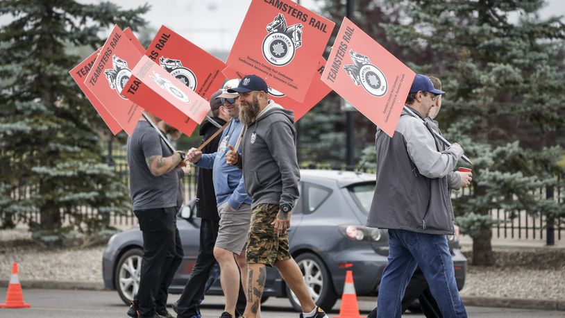 Teamsters Canada Rail Conference members walk a picket line at the CPKC headquarters in Calgary, Alberta, Thursday, Aug. 22, 2024. (Jeff McIntosh/The Canadian Press via AP)