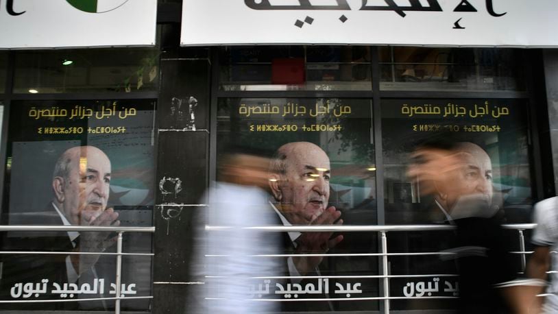 People walk past posters of Algerian President Abdelmadjid Tebboune, after the presidential election results were announced, Sunday, Sept. 8, 2024, in the capital Algiers. (AP Photo/Fateh Guidoum)