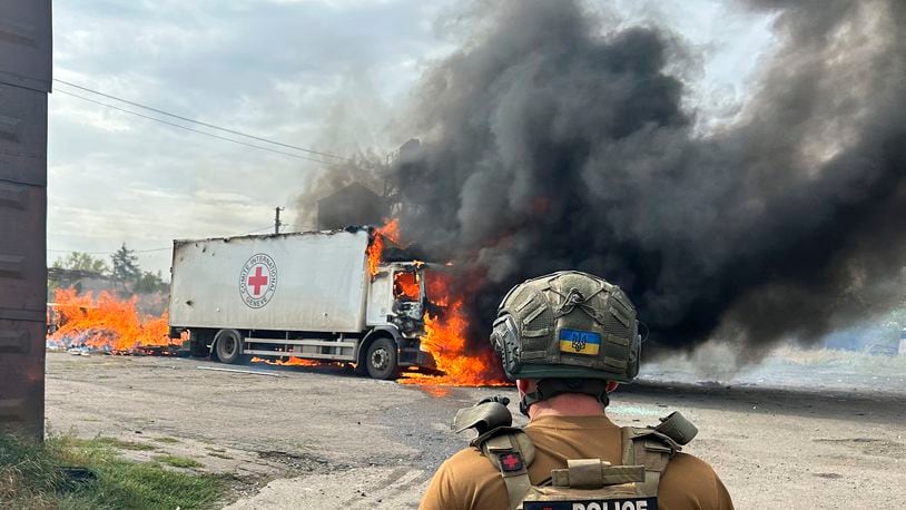 Image released by the Police of the Donetsk Region that shows a police officer looking at a burning Red Cross vehicle that was destroyed in a Russian strike in the Donetsk region on Thursday Sept. 12, 2024. (Police of the Donetsk Region via AP)