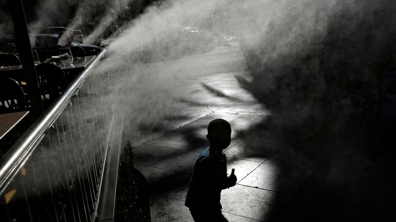 FILE - A child keeps cool beneath misters along the Las Vegas Strip, Friday, June 16, 2017, in Las Vegas. Pediatricians suggest keeping your child hydrated and avoiding prolonged sun exposure to keep heat illness at bay. (AP Photo/John Locher, File)