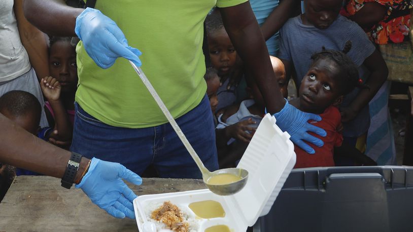 FILE - A server ladles soup into a container as children line up to receive food at a shelter for families displaced by gang violence, in Port-au-Prince, Haiti, March 14, 2024. Gang violence in Haiti has displaced over 300,000 children since March, according to a new report from the U.N. children's agency released late Tuesday, July 2, as the Caribbean country struggles to curb killings and kidnappings. (AP Photo/Odelyn Joseph, File)
