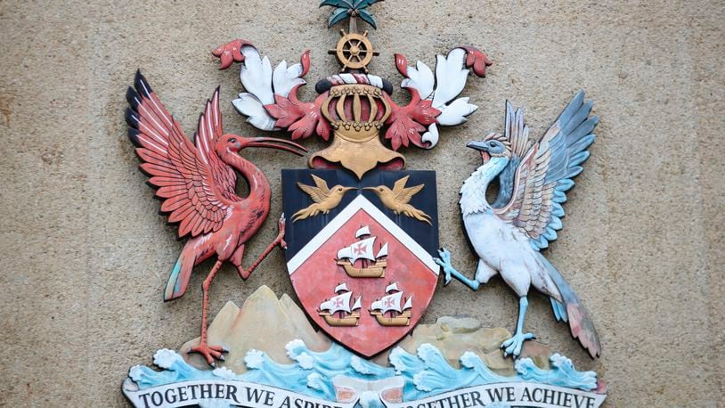 The country's coat of arms hangs at the entrance of a government building in Port-of-Spain, Trinidad and Tobago, Tuesday, Aug. 20, 2024. Prime Minister Keith Rowley announced on Sunday, Aug. 18, 2024, that the country is redrawing the island's coat of arms to remove references to European colonization, replacing Christopher Columbus' three ships with the steelpan, a popular percussion instrument. (AP Photo/Ash Allen)