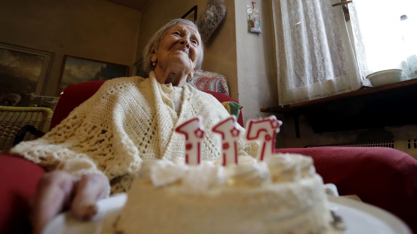 FILE- Emma Morano holds a cake with candles marking 117 years on the day of her birthday, Nov. 29, 2016, in Verbania, Italy. (AP Photo/Antonio Calanni)