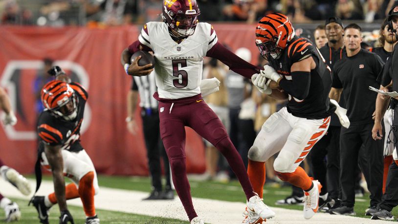 Washington Commanders quarterback Jayden Daniels (5) is tackled by Cincinnati Bengals linebacker Logan Wilson, right, during the second half of an NFL football game, Monday, Sept. 23, 2024, in Cincinnati. (AP Photo/Jeff Dean)