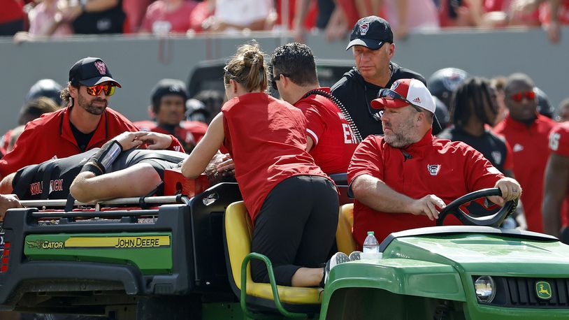 North Carolina State head coach Dave Doeren, rear right, checks on quarterback Grayson McCall (2) as he is carted from the field following an injury during the first half of an NCAA college football game in Raleigh, N.C., Saturday, Oct. 5, 2024. (AP Photo/Karl B DeBlaker)