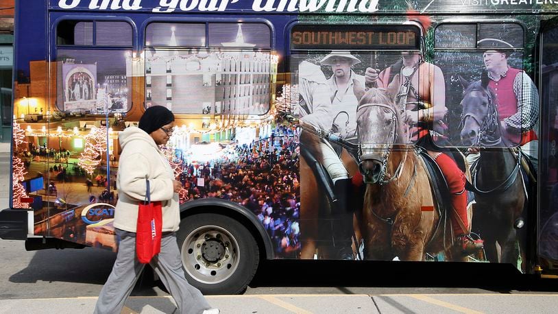 Lynn Perkins walks past the pictures on a SCAT bus at the transportation hub in downtown Springfield Monday, Nov. 6, 2023. BILL LACKEY/STAFF