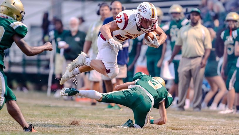 Northeastern High School senior Garrett Chadwell leaps over Catholic Central senior Owen Young during their game on Friday night at Hallinean Field in Springfield. The Jets won 20-7. Michael Cooper/CONTRIBUTED