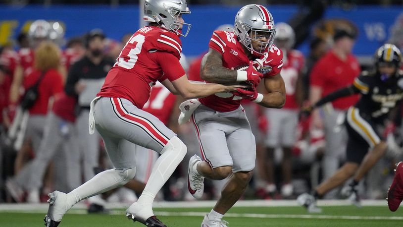 Ohio State quarterback Devin Brown, left, hands off to running back TreVeyon Henderson during the first half of the team's Cotton Bowl NCAA college football game against Missouri on Friday, Dec. 29, 2023, in Arlington, Texas. (AP Photo/Julio Cortez)