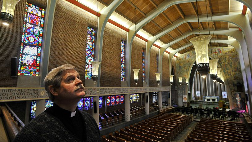 Andy Tune, pastor at Wittenberg University, looks over the stained glass windows in the university’s Weaver Chapel. Bill Lackey/Staff