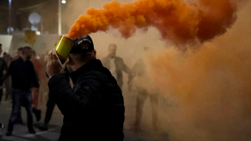 An opposition protester holds a flare during an anti-government rally set up by the opposition, in Tirana, Albania, Monday, Oct. 7, 2024. (AP Photo/Hameraldi Agolli)