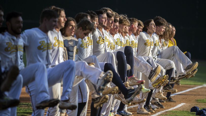 FILE- The Savannah Bananas line up along the first base line to perform a kick-line dance before a Coastal Plain League baseball game against the Florence Flamingos, June 7, 2022, in Savannah, Ga. (AP Photo/Stephen B. Morton, File)