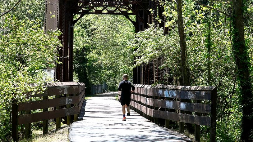 A man jogs across the steel bridge on the Simon Kenton Trail south of McCreight Avenue Wednesday, May 8, 2024. BILL LACKEY/STAFF