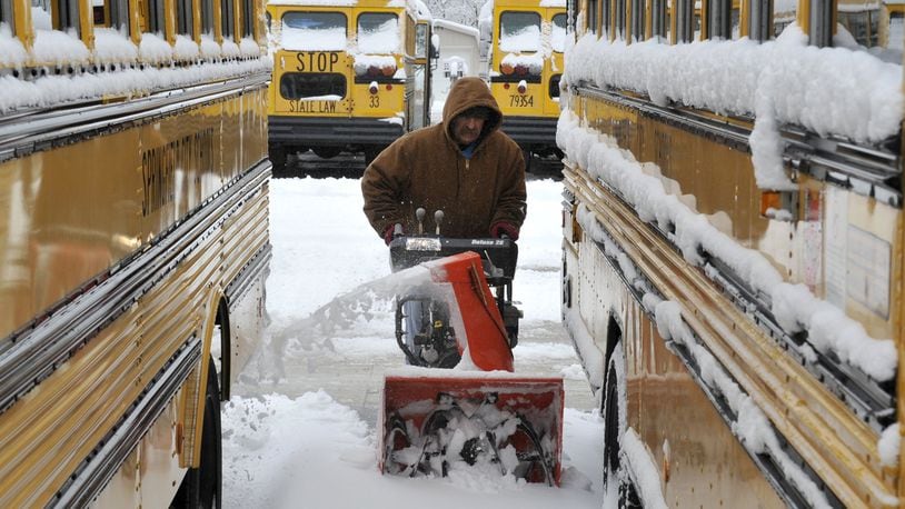 In this file photo from years ago, Tom Jenkins, a bus driver for Springfield City Schools, used a snow blower to clear a path between the school district’s buses. Schools in the area were closed Tuesday after snowy weather and freezing temperatures. FILE/Bill Lackey/Staff