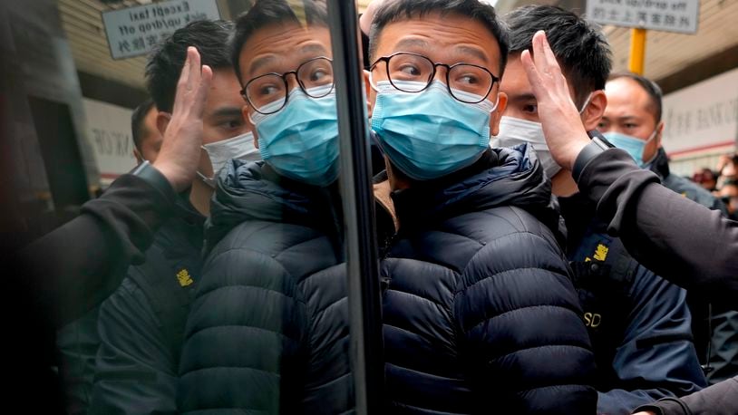 FILE - Then Editor of Stand News Patrick Lam, center, is escorted by police officers into a van after they searched evidence at his office in Hong Kong, Dec. 29, 2021. (AP Photo/Vincent Yu, File)