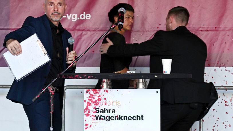 Sahra Wagenknecht, Chairwoman of the Sahra Wagenknecht Alliance (BSW), is escorted off the stage by a bodyguard following an attack with red paint during the election campaign event on Domplatz, Erfurt, Germany, Thursday Aug. 29, 2024. (Martin Schutt/dpa via AP)