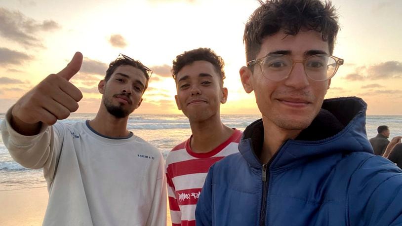 In this undated photo provided by Helmi Hirez, Mohamed (Medo) Halimy, left, and twin brothers Mohammed Hirez, center, and Helmi Hirez, right, stand on a beach in Gaza. (Helmi Hirez via AP).