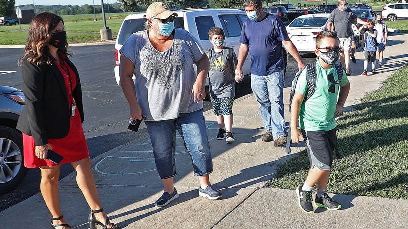 Triad Superintendent Vickie Hoffman, left, greets students and their families as they arrive for the first day of school on Thursday. Champaign County remains at a level 2, keeping district reopening plans the same. Clark County has upgraded to a level 3, but districts are also keeping their reopening plans the same as well. BILL LACKEY/STAFF