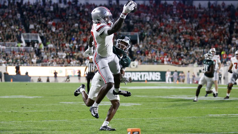 Ohio State wide receiver Jeremiah Smith, left, makes a one-handed catch for a touchdown against Michigan State defensive back Ed Woods during the first half of an NCAA college football game, Saturday, Sept. 28, 2024, in East Lansing, Mich. (AP Photo/Al Goldis)