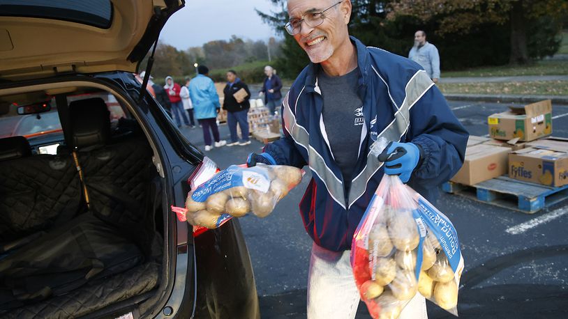 Tom Larger loads a car at the Second Harvest Food Bank food distribution at Clark State Monday, Nov. 6, 2023. BILL LACKEY/STAFF