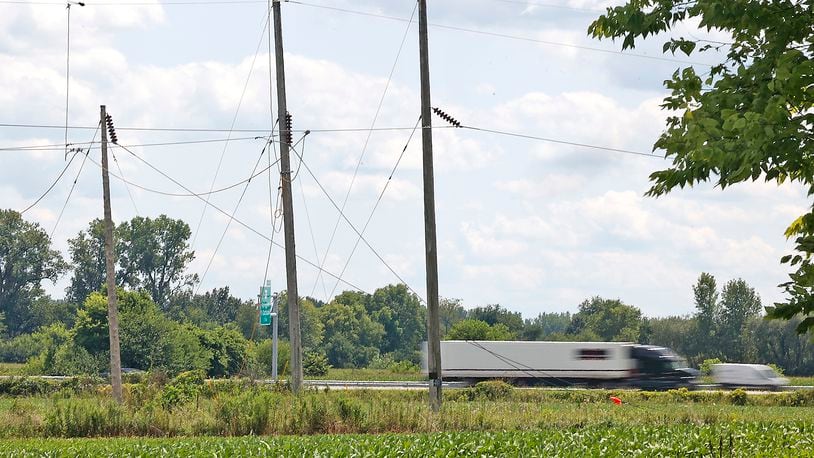 Traffic speeds by on Interstate 70 Monday, July 31, 2023. The interstate was closed for several hours Saturday after a helicopter accidentally cut the power lines, pictured in the foreground, that stretch over the roadway. BILL LACKEY/STAFF