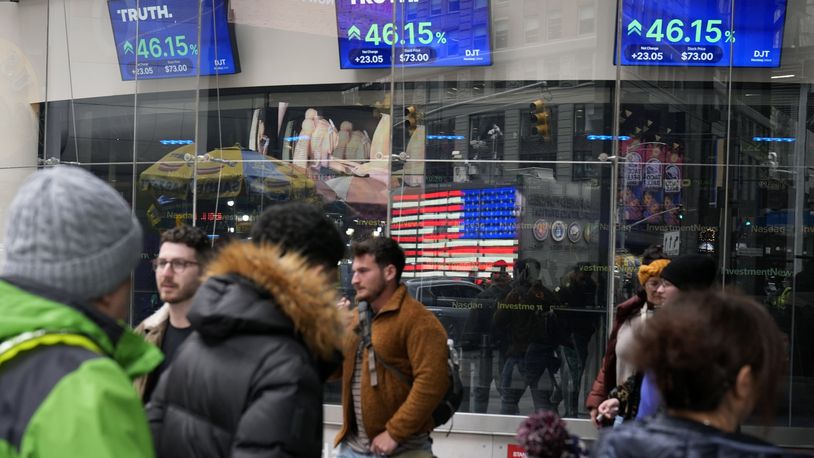 FILE - Pedestrians walk past the Nasdaq building as the stock price of Trump Media & Technology Group Corp. is displayed on screens, March 26, 2024, in New York. (AP Photo/Frank Franklin II, File)