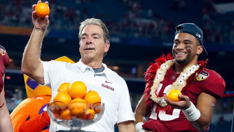 Alabama head coach Nick Saban and quarterback Tua Tagovailoa throw oranges to the team during the Orange Bowl NCAA college football game trophy presentation Sunday in Miami Gardens, Fla.