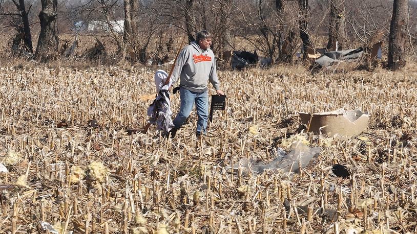 Kevin Martin picks up parts of his son's house that were blown into a corn field Thursday, Feb. 29, 2024 as he helps him clean up after Wednesday's tornado. BILL LACKEY/STAFF