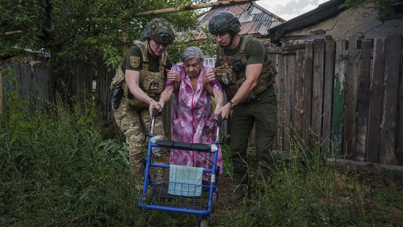Police officers of the White Angels unit help an elderly woman walk into a van during an evacuation to safe areas, in Toretsk, Donetsk region, Ukraine, Friday, June 28, 2024. (AP Photo/Evgeniy Maloletka)